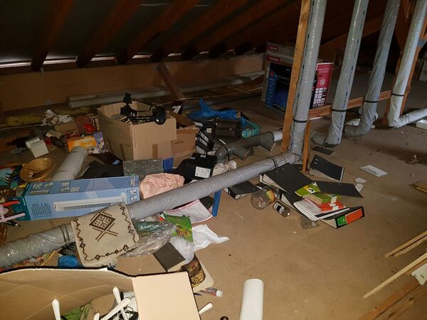 Dachboden mit herumliegendem Gerümpel, Kartons, Aktenordnern und Lüftungsrohren.