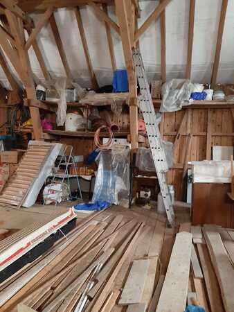 Dachboden mit Holzlager, Leiter, Baumaterial und Werkzeugen für Renovierung oder Ausbau.