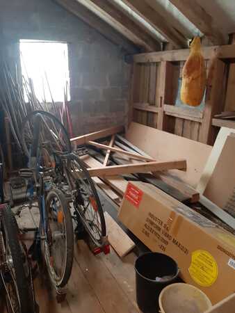 Dachboden mit alten Fahrrädern, Holzlatten, Kartons und aufgehängtem Schinken.